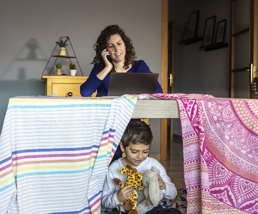 Mother working at home while her son plays