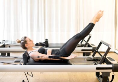 Women using her Home Pilates Reformer to work abdominals in curl up with legs straight