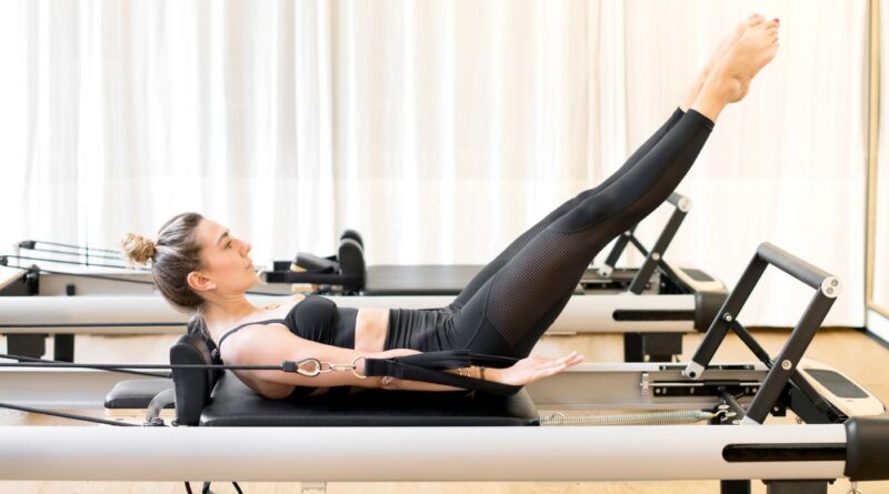 Women using her Home Pilates Reformer to work abdominals in curl up with legs straight