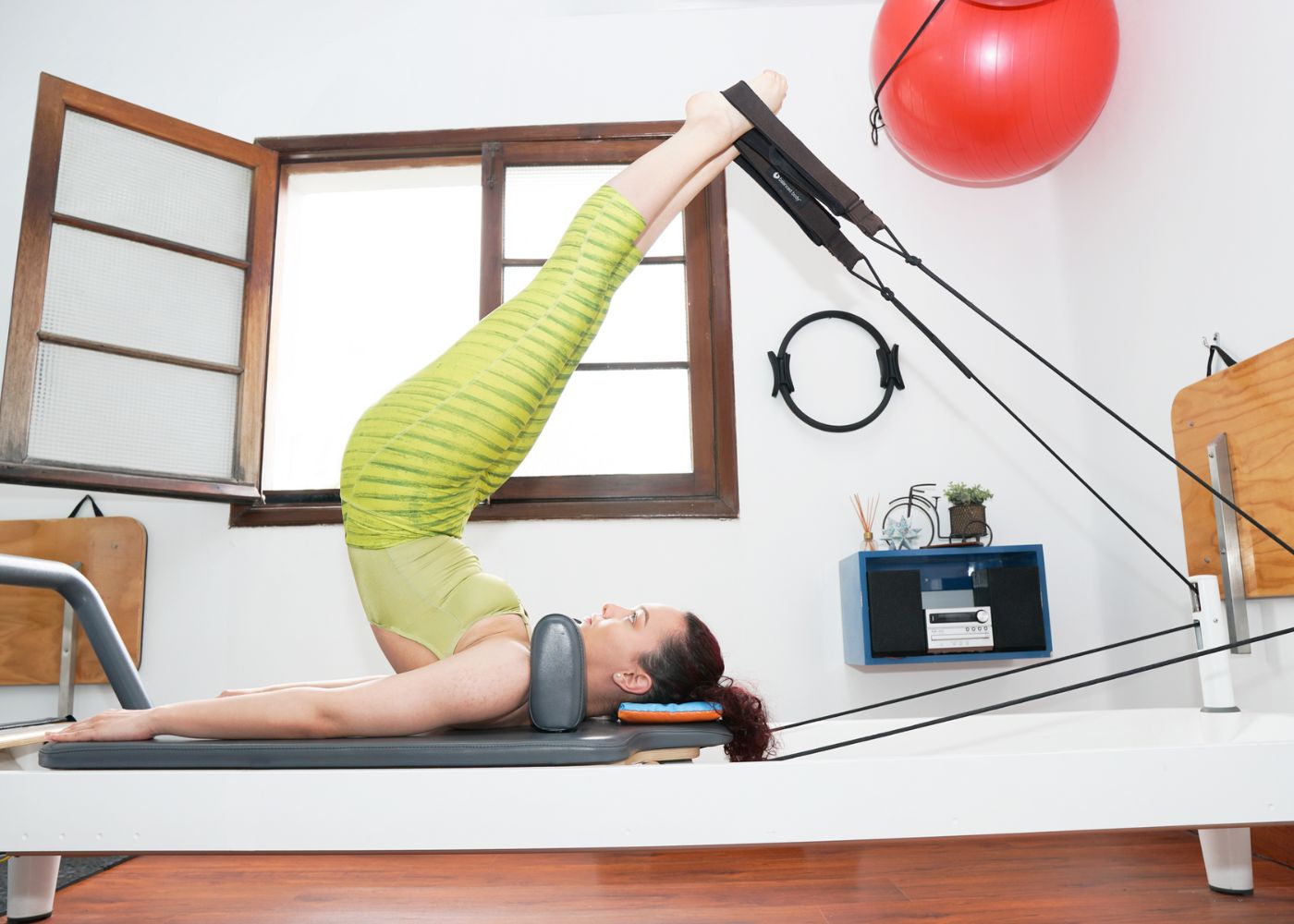Woman with feet in straps on her Body Balanced Allegro 2 Reformer working out from home